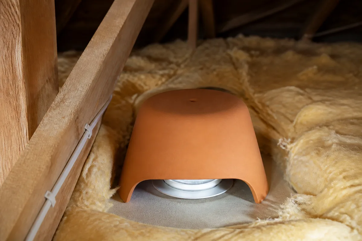 Capot de protection rigide posé au-dessus d’un spot encastré avant la pose de l’isolant